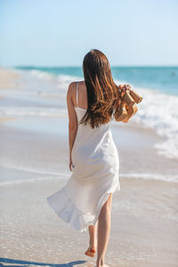 Rear view of woman standing at beach