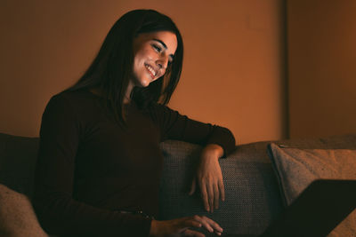 Young woman sitting on sofa at home