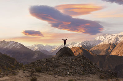 Rear view of man standing on mountain against sky during sunset