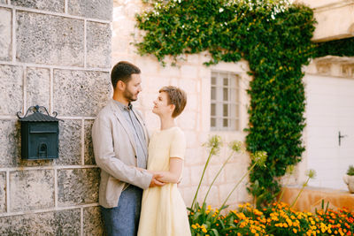 Young couple standing by wall outdoors