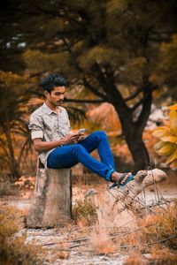 Full length of young man sitting on stone wall