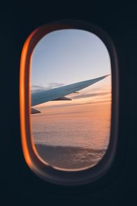 View from window of airplane during flight above clouds at beautiful sunset.