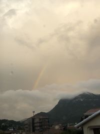 Rainbow over buildings in city against sky