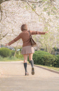 Full length rear view of woman walking on road