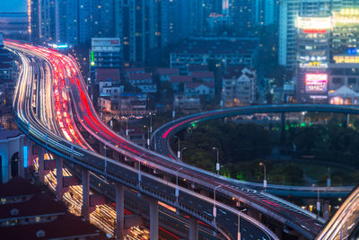 Light trails on street amidst buildings in city at night