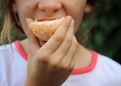 Midsection of girl eating orange