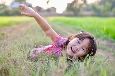 Portrait of cheerful girl lying at rice paddy during sunset