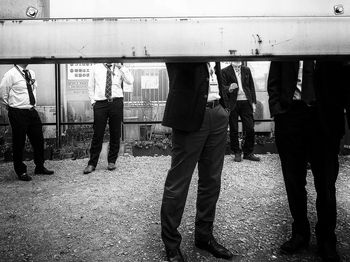 Rear view of people standing on railroad track