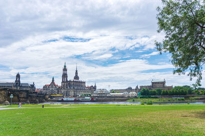 View of temple by building against cloudy sky