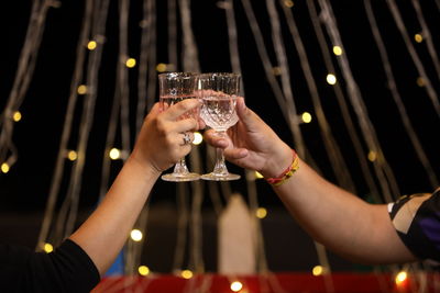 Cropped hands of man and woman toasting wineglass