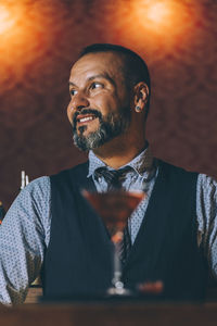 Mature man with drink on table looking away while sitting in restaurant