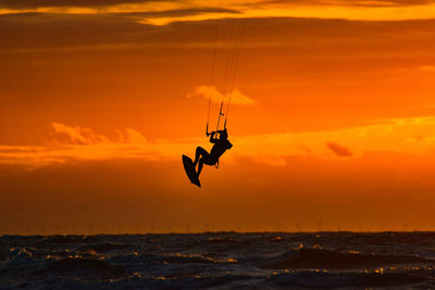 Silhouette people on sea against sky during sunset