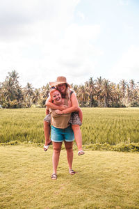 Portrait of happy friends standing on field against sky