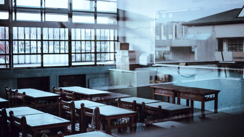 Empty chairs and tables in building seen through glass window