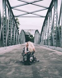 People sitting on bridge against sky