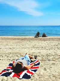 Woman relaxing at beach against sky