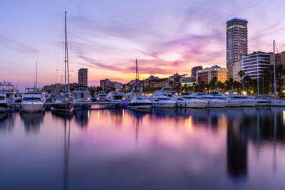 Sailboats moored in harbor against sky at dusk