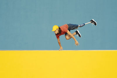 Man with physical disability jumping against multi colored wall