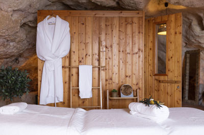 White bathrobe hanging on wooden wall in hotel room