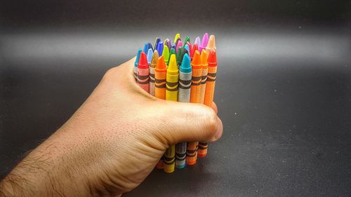 Close-up of person holding multi colored pencil