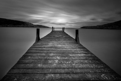 Surface level of wooden pier over sea against sky