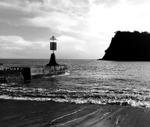 Lighthouse on beach against sky