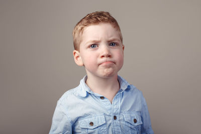 Portrait of cute boy against gray background