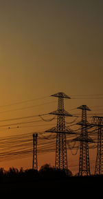 Low angle view of silhouette electricity pylon against sky during sunset