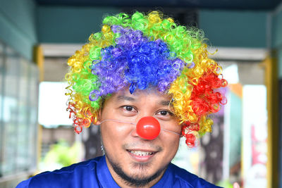 Portrait of man wearing multi colored wig and clown at home