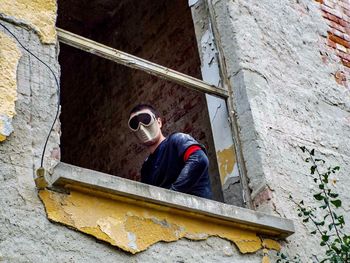 Low angle view of man wearing mask at window