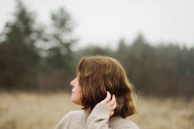 Woman standing by forest in foggy weather