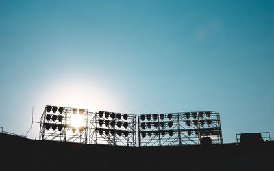 Low angle view of illuminated floodlights on stadium against clear sky