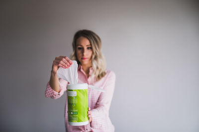 Young woman drinking glass against white background