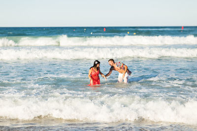 People enjoying at beach against sky