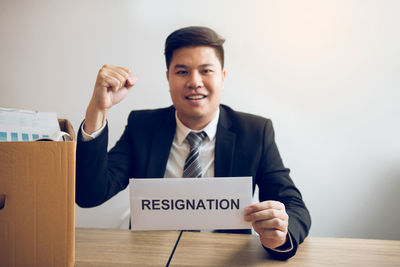 Portrait of smiling businessman holding resignation letter at desk in office