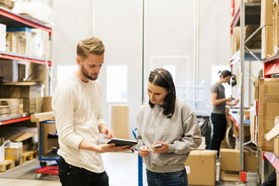 Coworkers looking at digital tablet while planning in distribution warehouse