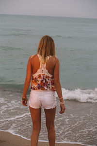 Rear view of young woman standing on beach