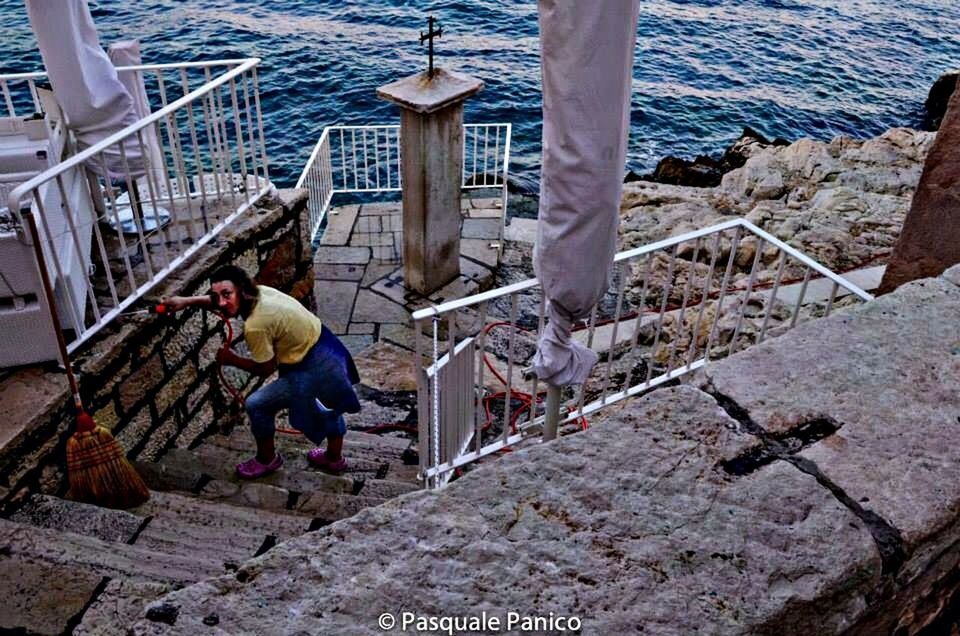 water, high angle view, railing, steps, built structure, pier, sea, rear view, architecture, day, nautical vessel, sunlight, staircase, full length, leisure activity, lifestyles, person, outdoors, men