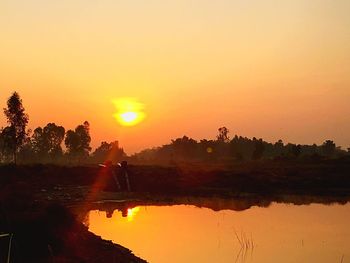 Scenic view of lake against orange sky