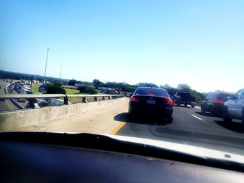 Cars on road against sky seen through car windshield