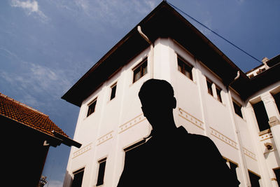 Low angle view of people on house against sky