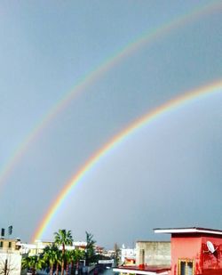 Rainbow over city against sky