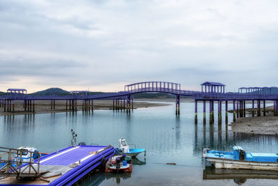 Boats moored at harbor against sky