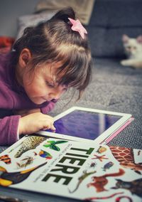 Side view of cute girl using digital tablet at home