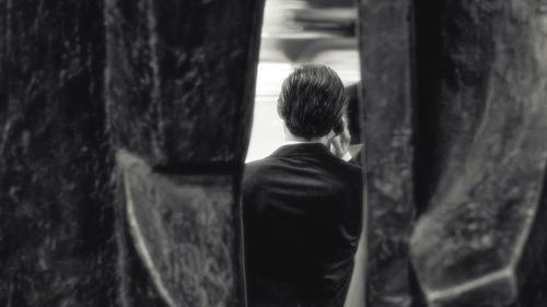 Rear view of boy standing by tree trunk