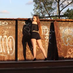 Full length portrait of woman standing against wall