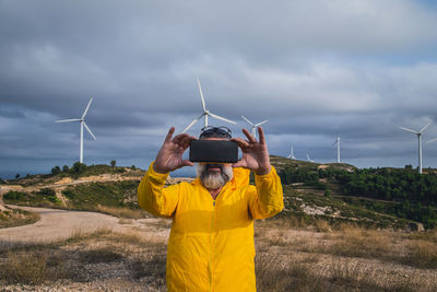 Man taking selfie near wind turbines at sunset