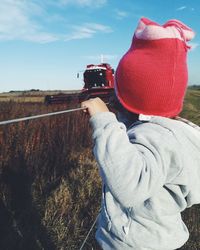 Close-up of kid wearing warm clothing while looking at combine harvester