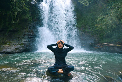 Female tourist playing in the waterfall