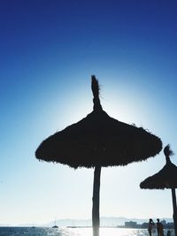 Low angle view of silhouette palm tree on beach against clear blue sky